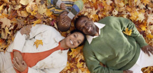 family lying in a leaf pile looking up