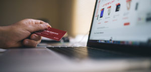 man looking to make purchase on her laptop with a credit card in his left hand